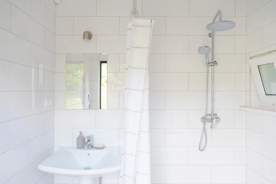 A bathroom with a hot rain shower and a window onto the trees